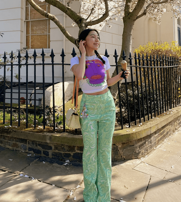 chica de cabello oscuro usando una camiseta blanca con morado, pantalones verde menta con blanco