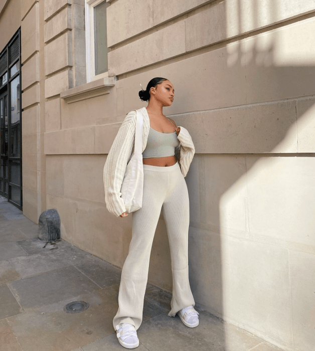 chica morena con crop top verde menta, cárdigan blanco tejido, pantalones ajustados blancos acampanados, tenis blancos