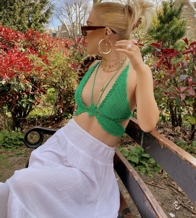 chica de cabello rubio usando lentes de sol, crop top verde brillante tejido, falda larga blanca de gaza