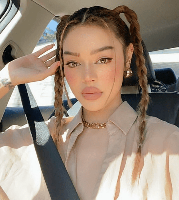 chica de cabello claro con trenzas altas, camisa beige de vestir y top beige