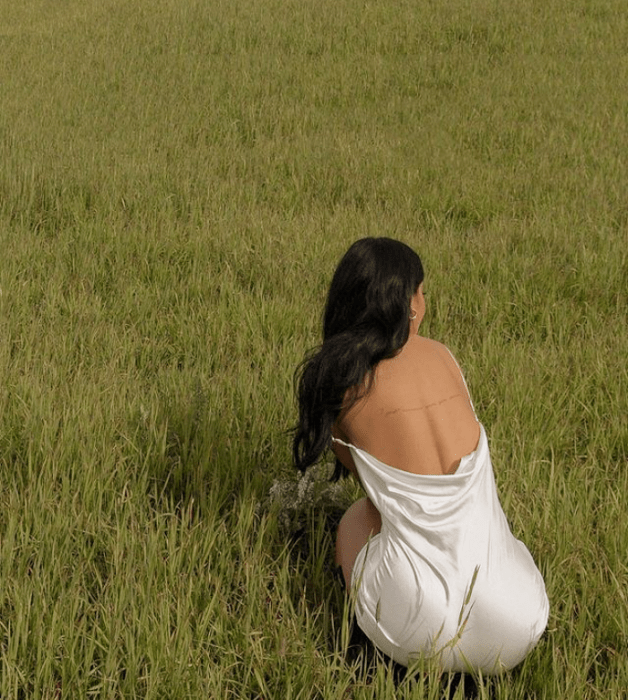 chica de cabello castaño largo usando un vestido de satén color beige claro