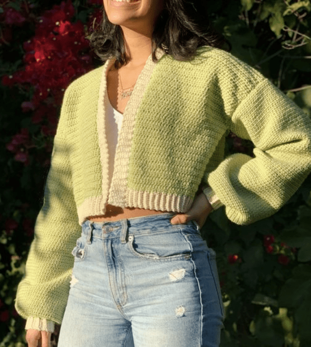 chica de cabello oscuro con top blanco, cárdigan verde pistache, jeans ajustados