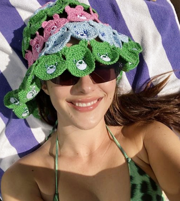 chica con cabello oscuro usando lentes de sol negros, bikini verde con café, bucket hat tejido verde con azul celeste y rosa claro