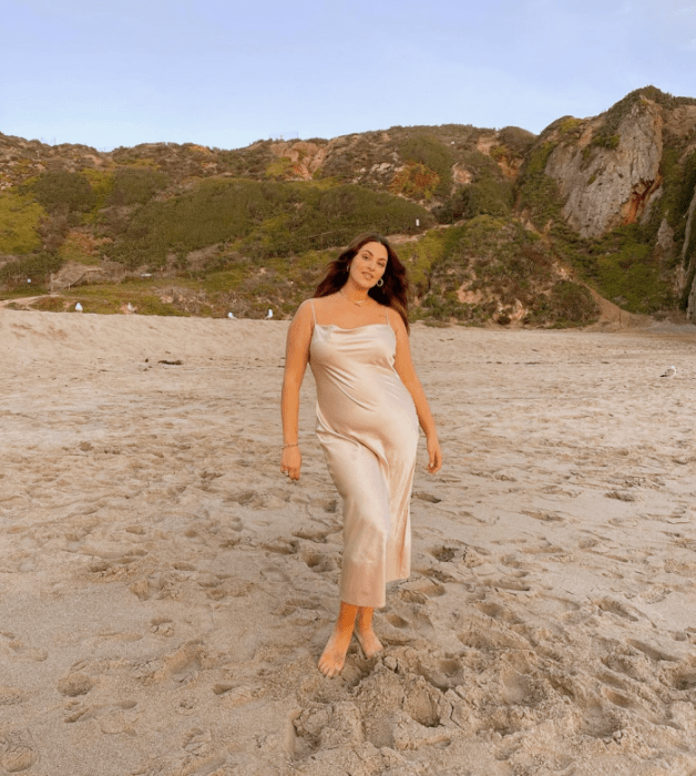 chica de cabello castaño usando un vestido de satén color champaña largo de tirantes