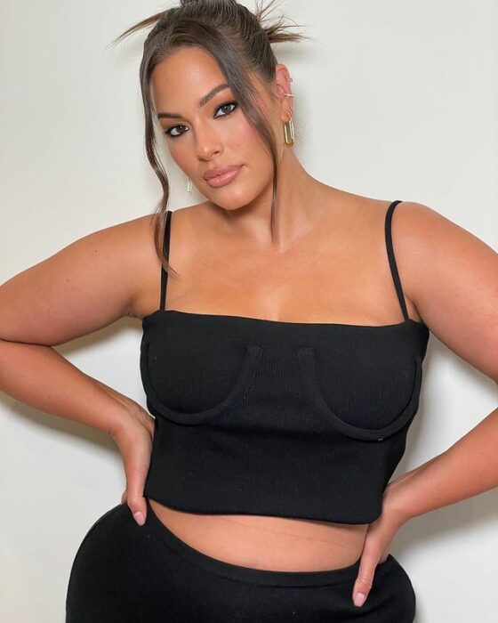 Ashley Graham posando para una sesión de fotos mientras un outfit de color negro