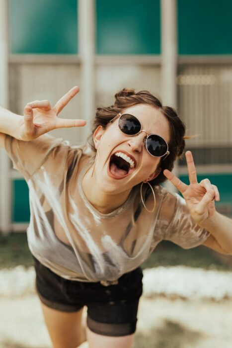 chica haciendo señas y sonriendo ;Así es como afecta el estrés a tu salud bucal y no lo sabías