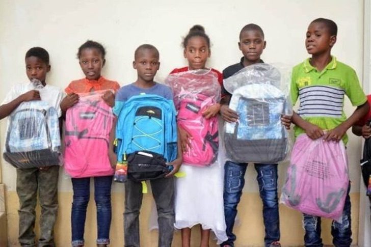 Chicos de haití sosteniendo varias mochilas en sus manos 