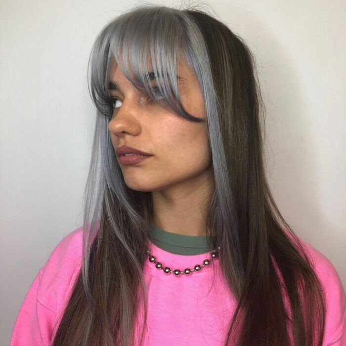 Chica usando un fleco estilo Walft con el cabello largo y teñido de gris con negro 