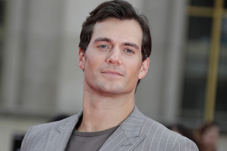 Henry Cavill usando un traje de color gris mientras está sonriendo