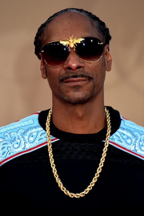 Snoop Dogg usando una sudadera negra con lentes y cadena de oro 