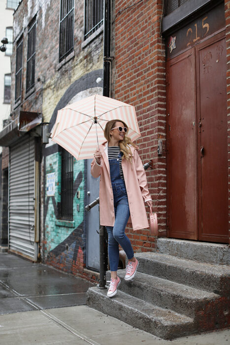 Chica usando un outfit de lluvia con botas, paraguas y chaqueta