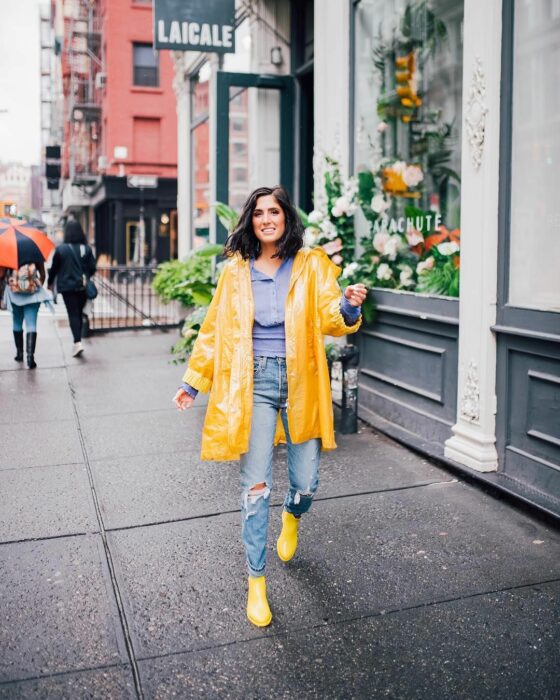 Chica usando un outfit de lluvia con botas, paraguas y chaqueta