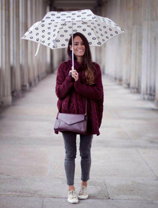 Chica usando un outfit de lluvia con botas, paraguas y chaqueta