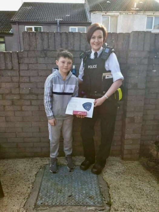 Mujer policía entregando un reconocimiento a un niño