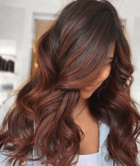 Chica con el cabello teñido en color chocolate con reflejos rojos 