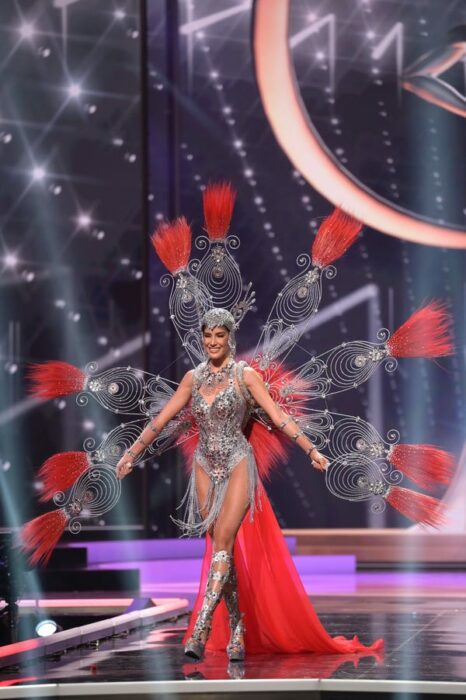 Miss universo usando su traje típico en color rojo con plumas