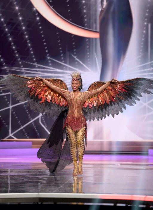 Miss universo usando su traje típico en forma de aguila en colores rojo con negro