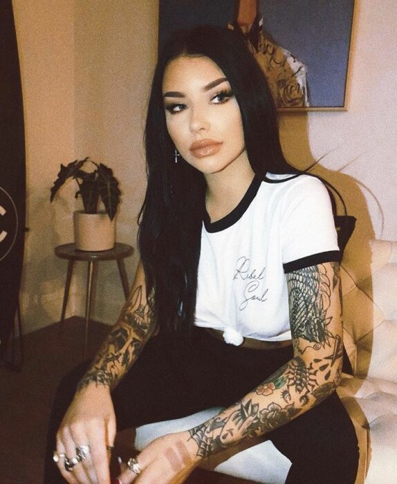 chica con tatuajes sentada sobre una cama ;4 Tips para cuidar tus tatuajes y no sufrir en el intento