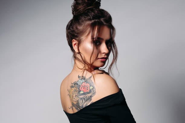 chicsa mostrando el tatuaje de su espalda; 4 Tips para cuidar tus tatuajes y no sufrir en el intento