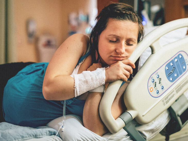 Mujer embarazada sujetando la cama del hospital 