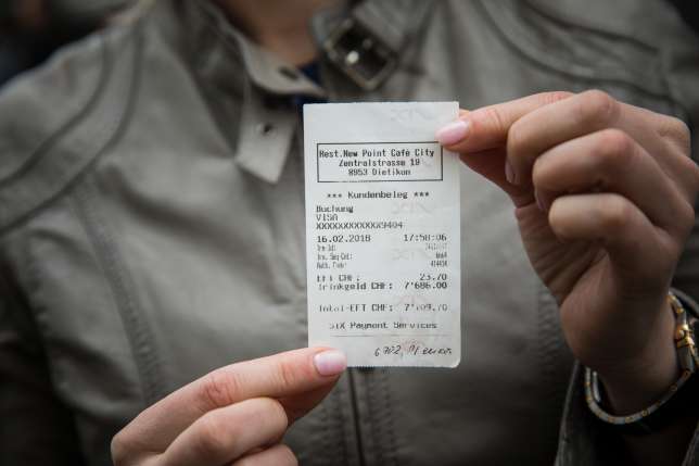 Mujer sosteniendo un ticket de compras; Fue por una taza de café y por un descuido terminó pagando casi 8 mil dólares