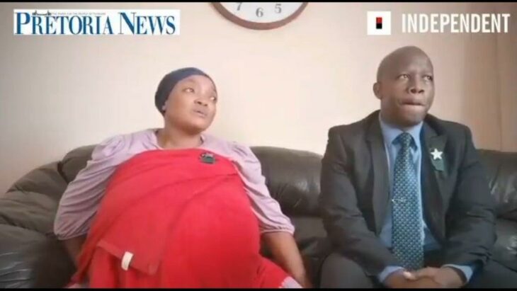Mujer sudafricana con un enorme vientre de embarazo sentada junto a su pareja 