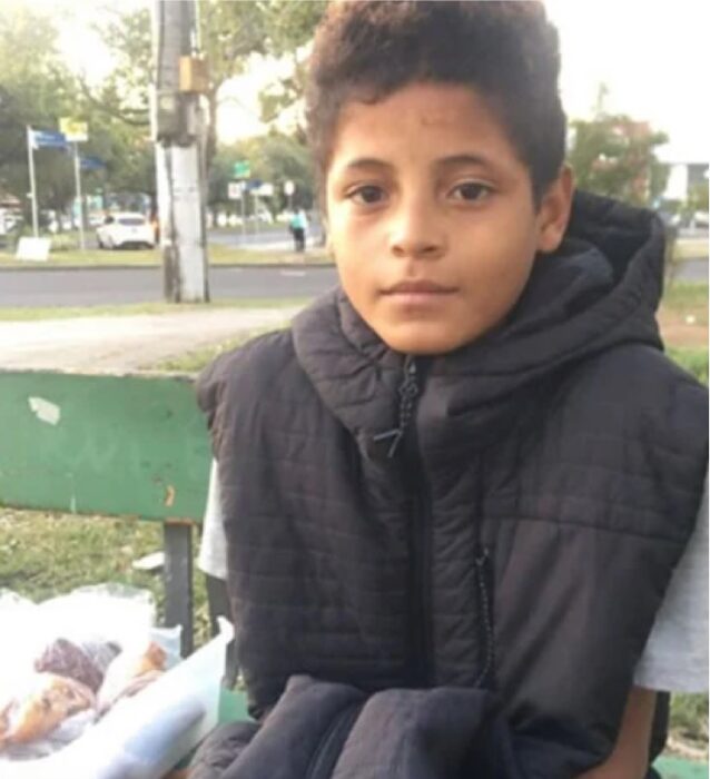 Niño sentado en la banca de un parque vendiendo pasteles 