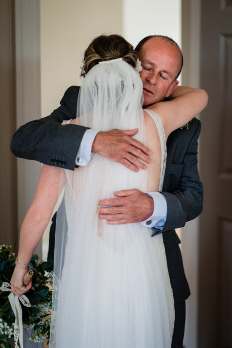 Padre e hija sonriendo el día de la boda mientras se ven por primera vez