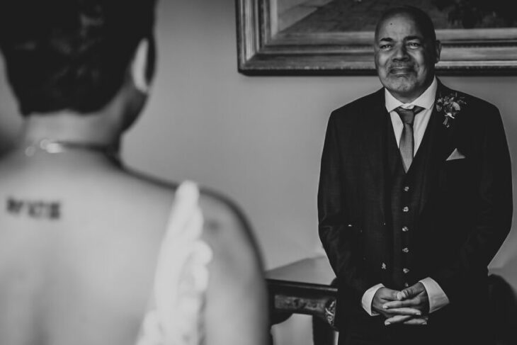 Padre e hija sonriendo el día de la boda mientras se ven por primera vez