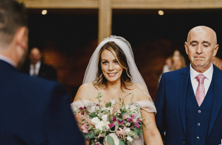 Padre e hija sonriendo el día de la boda mientras se ven por primera vez