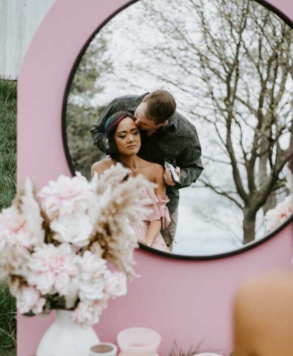 Pareja posando para una sesión de fotos mientras están frente a un espejo