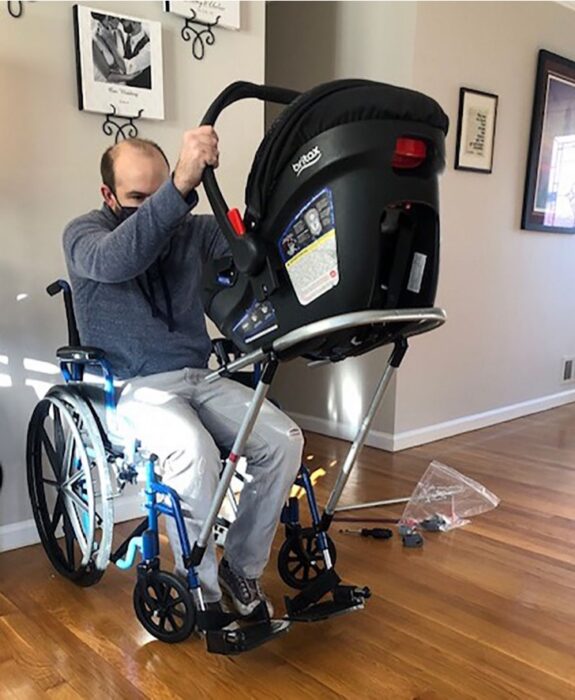 Man in a wheelchair walking his baby in a baby carrier 