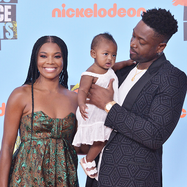 Gabrielle Union and her husband posing with their daughter in a photo