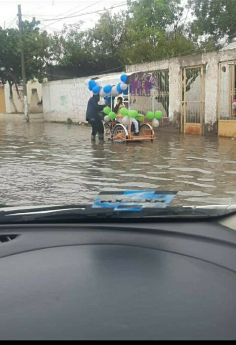 Hombre caminando en la lluvia mientras lleva a su hijo en un triciclo adornado con globos 