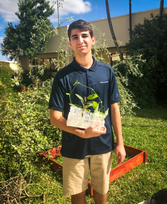 Ducan sosteniendo una maceta con flores ;Joven siembra miles de flores durante 12 años y logra salvar a cientos de mariposas en extinción