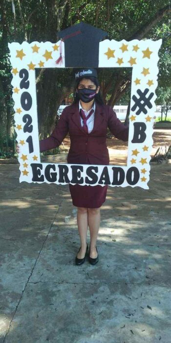 Mujer sosteniendo un marco de graduación ;Mamá soltera se titula como profesora luego de vender pan y sopa en las calles