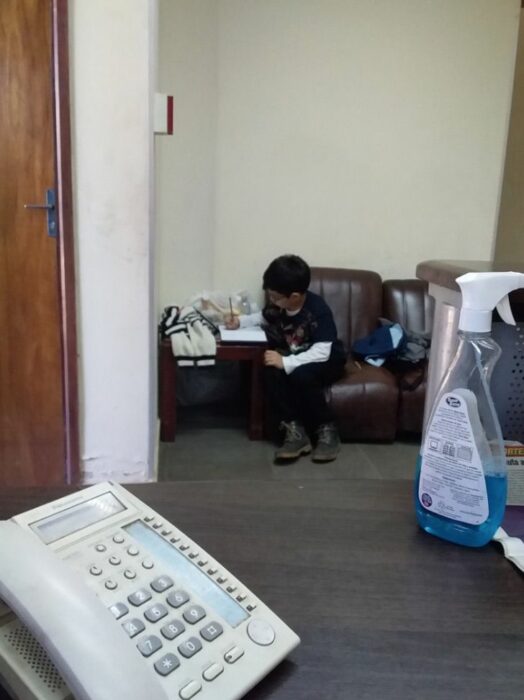 Niño sentado en un sofá haciendo tarea ;Niño acompaña a su mamá al trabajo para hacer sus tareas y se vuelve viral