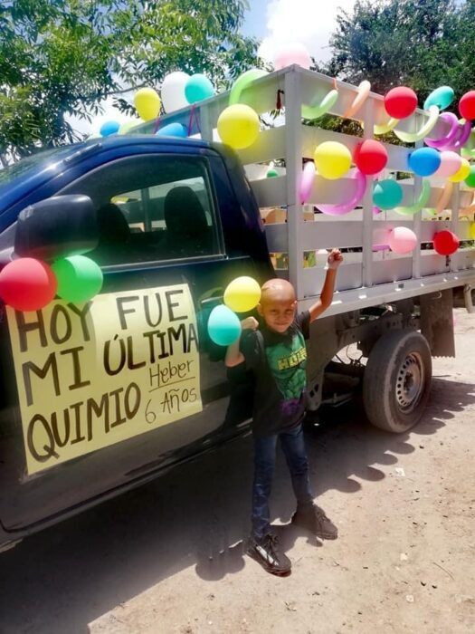 Niño posando junto a una camioneta llena de globos 