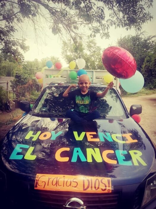 Niño posando junto a una camioneta llena de globos 