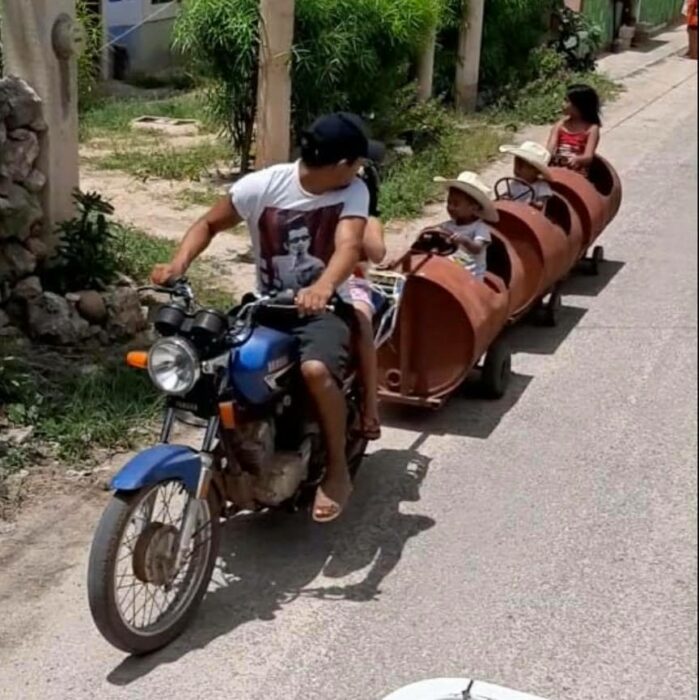 padre e hijos de paseo; Papá crea trenecito con botes de metal para sus hijos