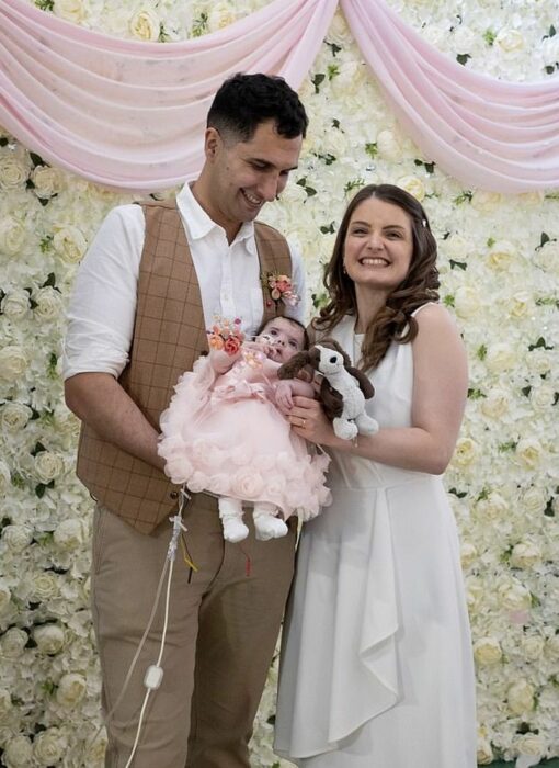 Pareja sosteniendo a su bebé el día de su boda 