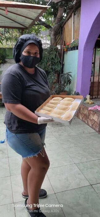 Chica sosteniendo una charola de empanadas ;Vende empanadas caseras para cumplir su sueño de ser militar e internet ya salió al rescate