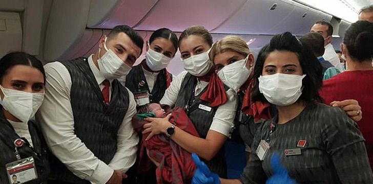 Asistentes de vuelo sosteniendo a una bebé que nació durante un viaje 