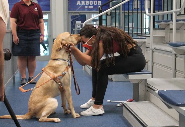 Chica acariciando a su perro; Nadadora ciega y su perro guía van en pareja a los Juegos Paralímpicos