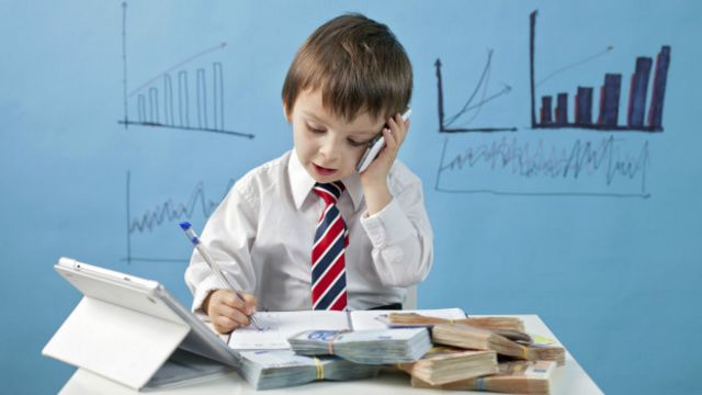 Niño haciendo negocios mientras está sentado en un escritorio 