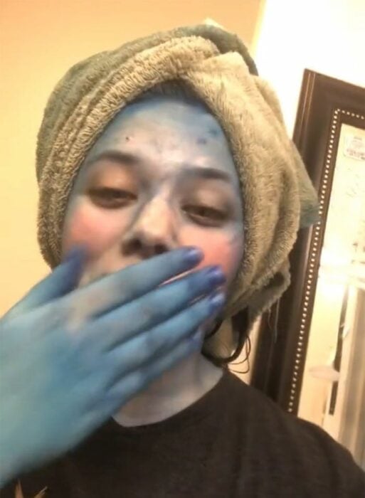 Chica mirando su cuerpo teñido de azul al teñir su cabello 