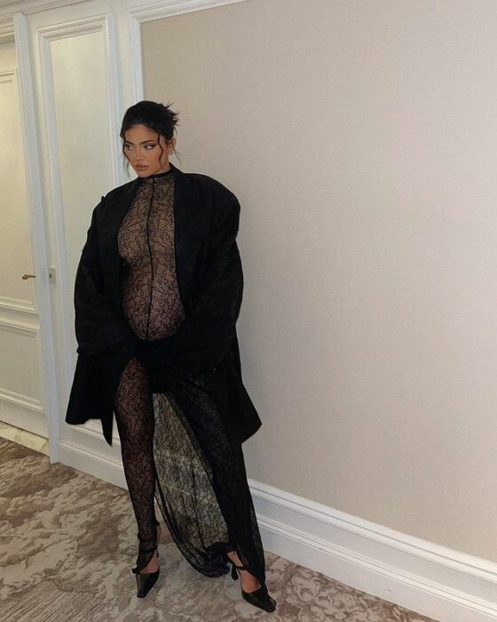 Kylie Jenner posando con un atuendo negro mientras muestra su pancita de embarazo 