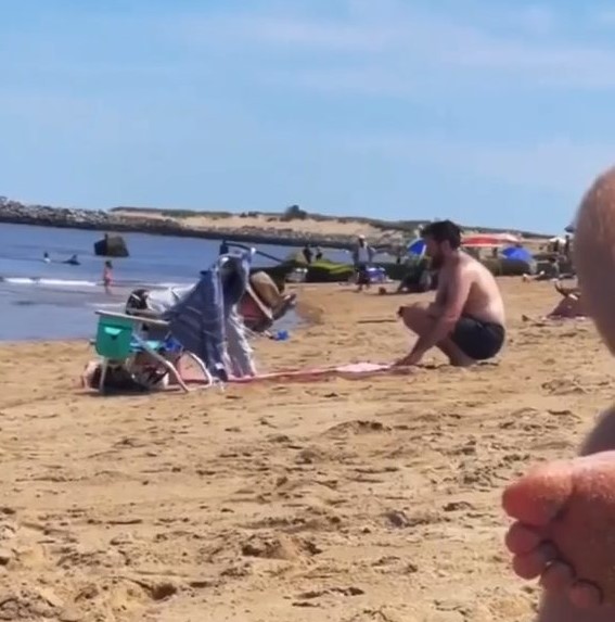 Man digging a hole on the beach for his wife to lie on 