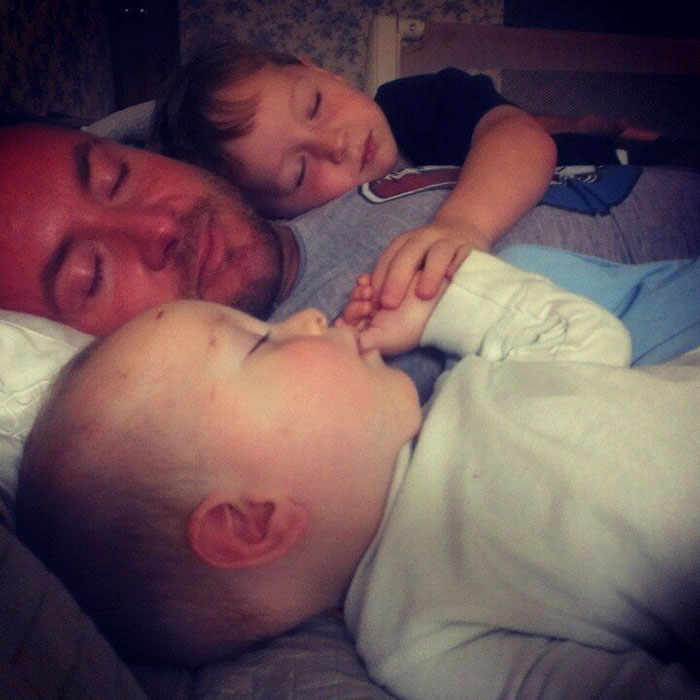 Dad lying next to his sleeping children 