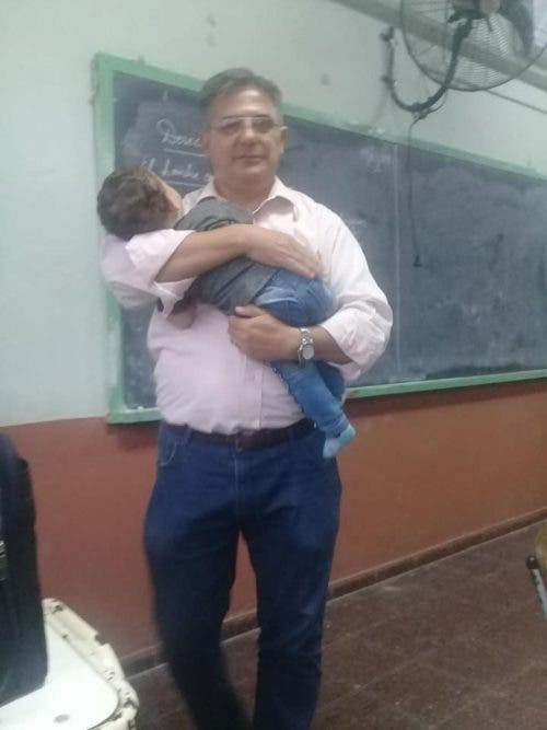 Hombre cargando a un bebé, Profesor cuida del bebé de su alumna para que pueda tomar su clase